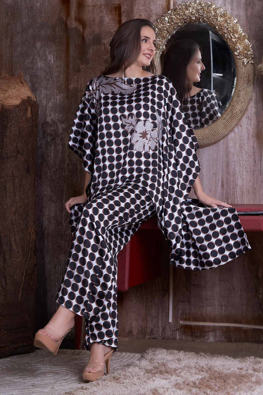 Model wearing a black and white polka dot two-piece set with wide-leg pants and a poncho, ideal for fashion forward attire.
