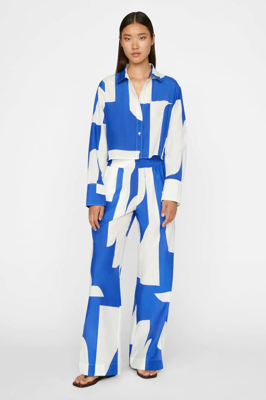 A model wears a co-ord set with a dynamic blue and white abstract wave pattern, comprising a buttoned shirt and wide-leg trousers