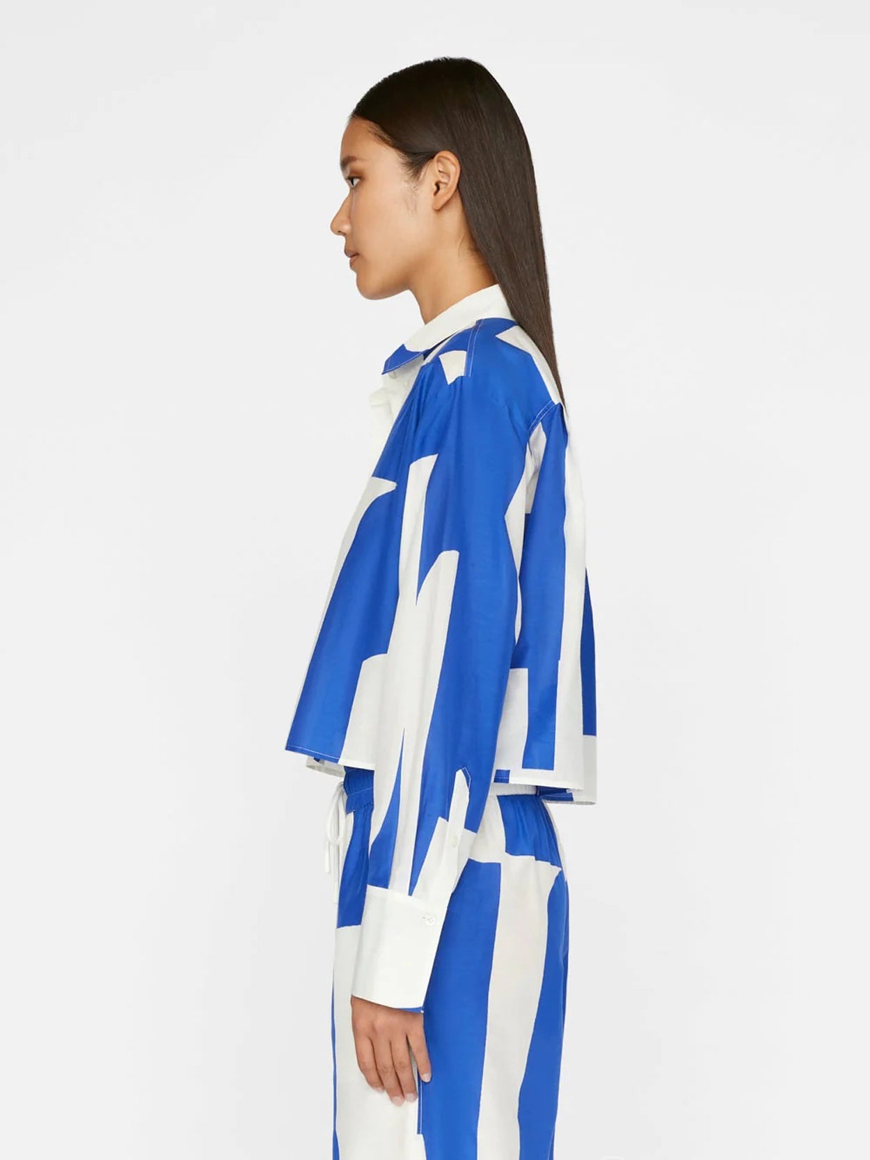 A model wears a co-ord set with a dynamic blue and white abstract wave pattern, comprising a buttoned shirt and wide-leg trousers