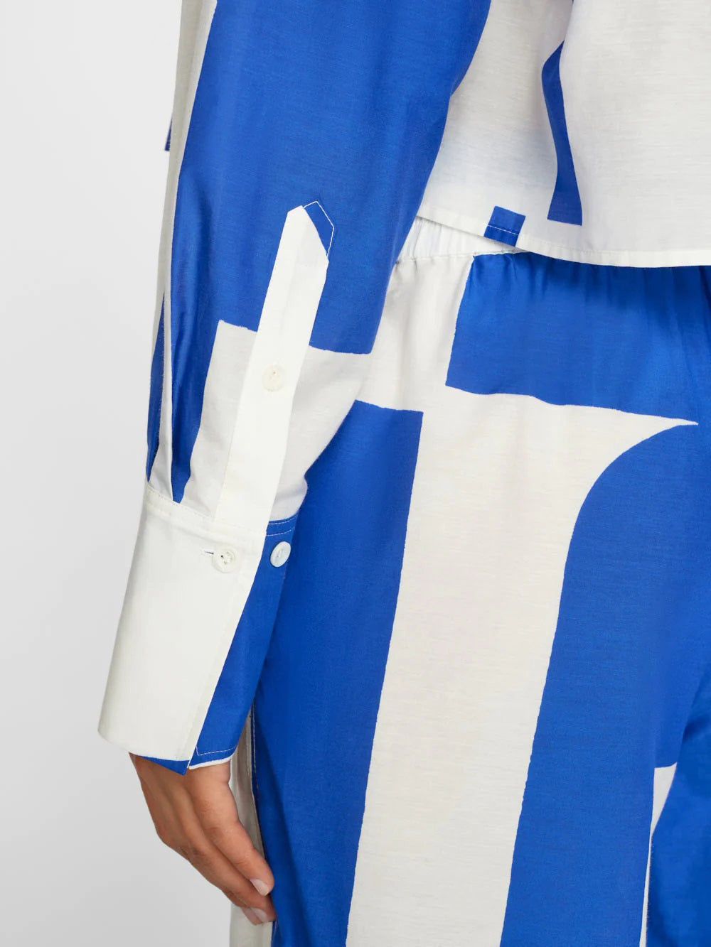 A model wears a co-ord set with a dynamic blue and white abstract wave pattern, comprising a buttoned shirt and wide-leg trousers