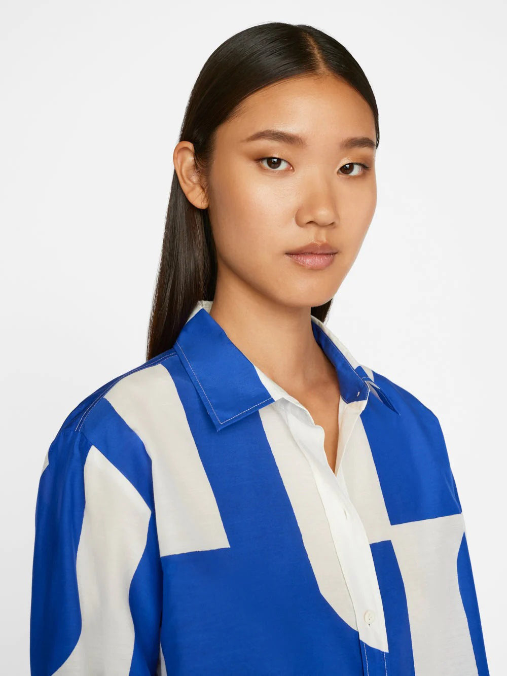 A model wears a co-ord set with a dynamic blue and white abstract wave pattern, comprising a buttoned shirt and wide-leg trousers