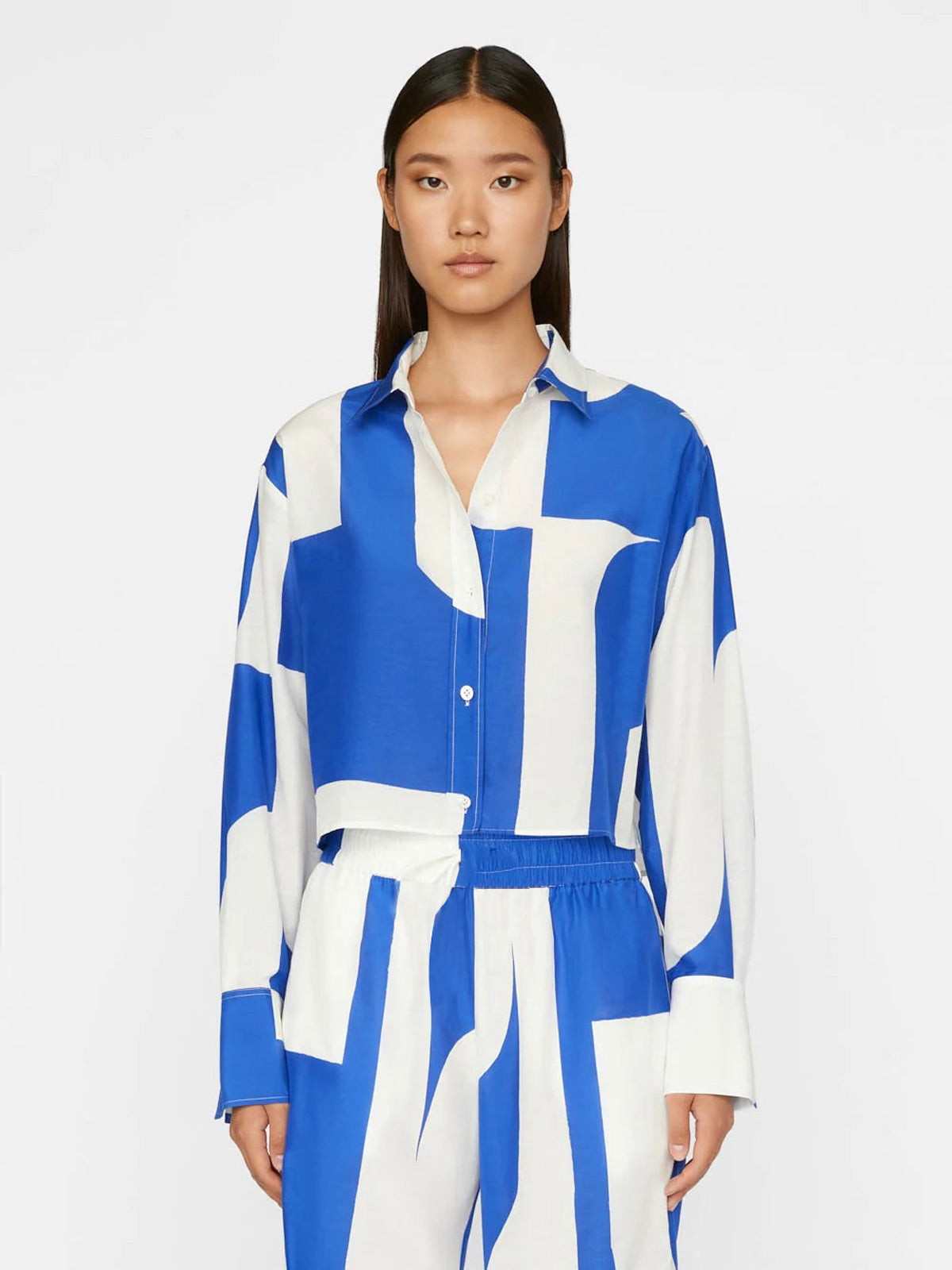 A model wears a co-ord set with a dynamic blue and white abstract wave pattern, comprising a buttoned shirt and wide-leg trousers