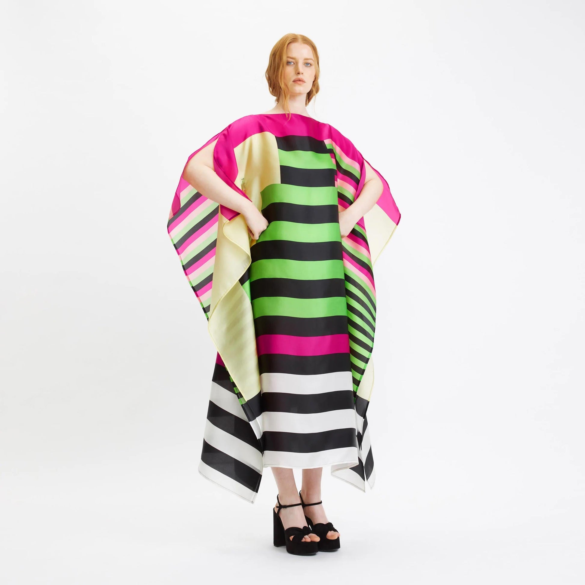 A vibrant striped silk kaftan with bold color block patterns in pink, green, black, and white.