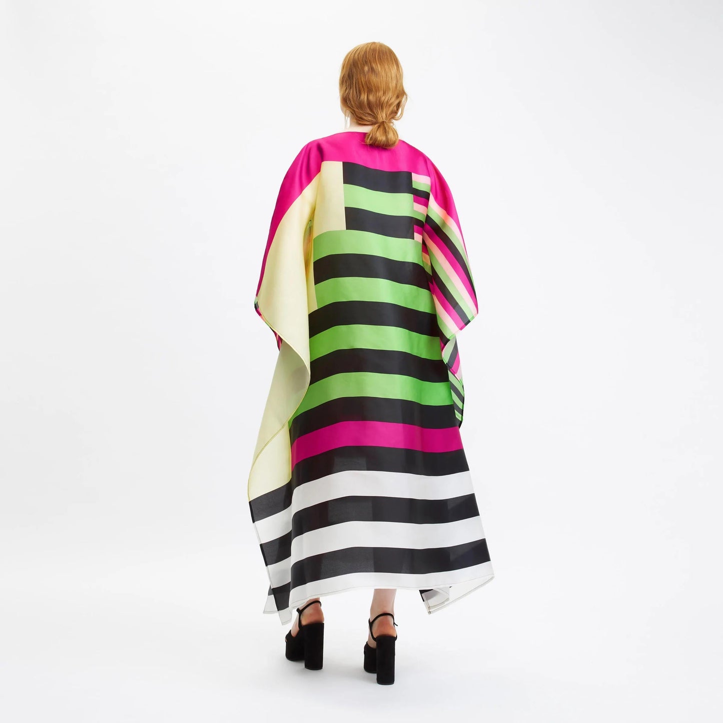 A vibrant striped silk kaftan with bold color block patterns in pink, green, black, and white.