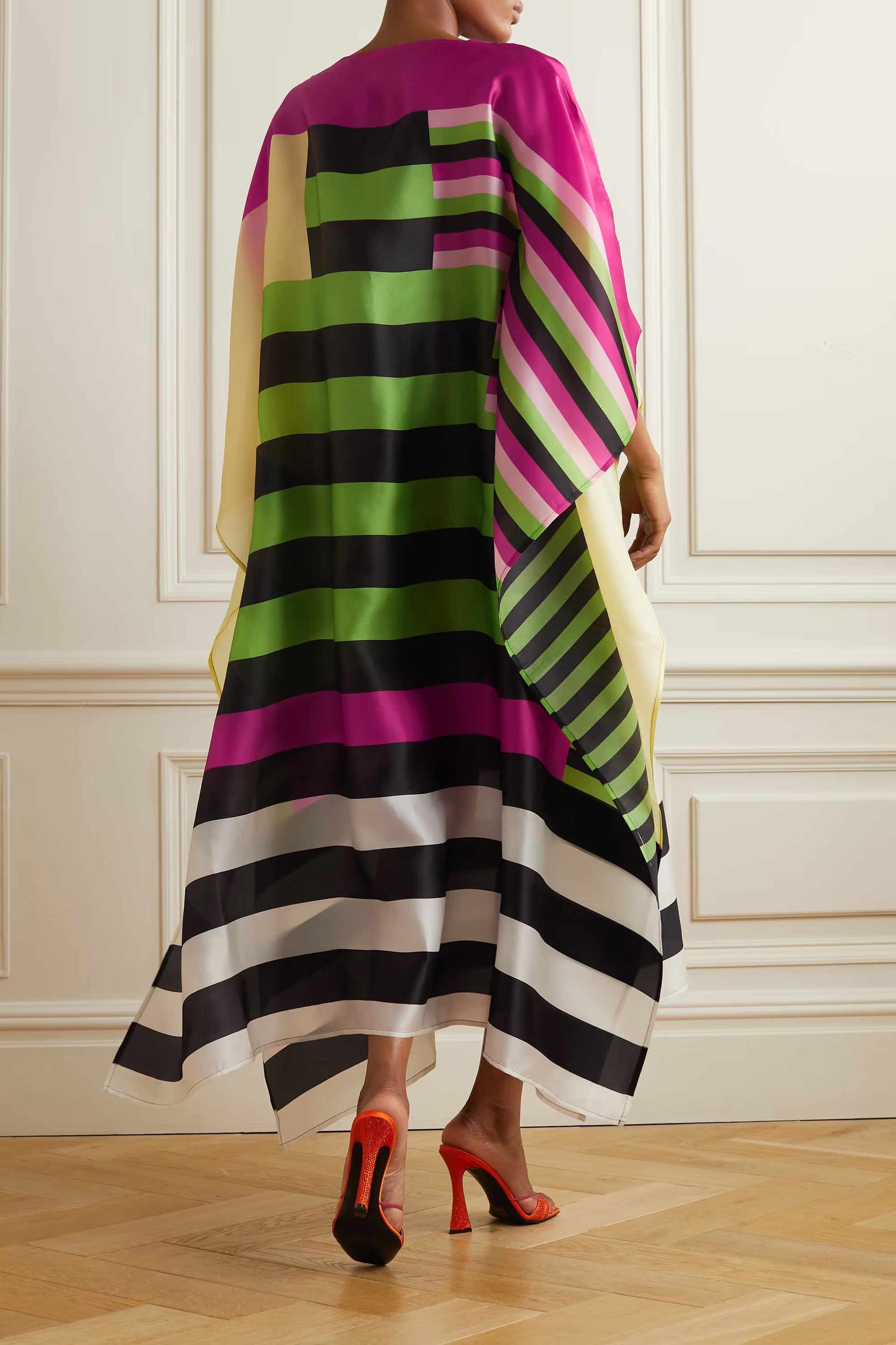 A vibrant striped silk kaftan with bold color block patterns in pink, green, black, and white.